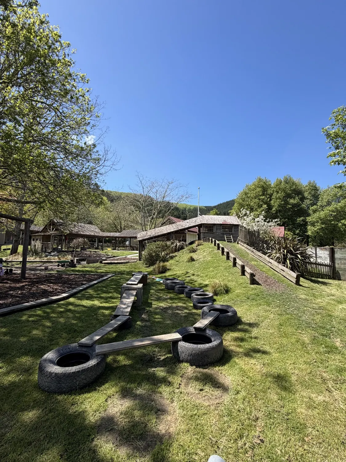 The outdoor playground at The Farmyard on a sunny day, with an obstacle course of tyres and planks