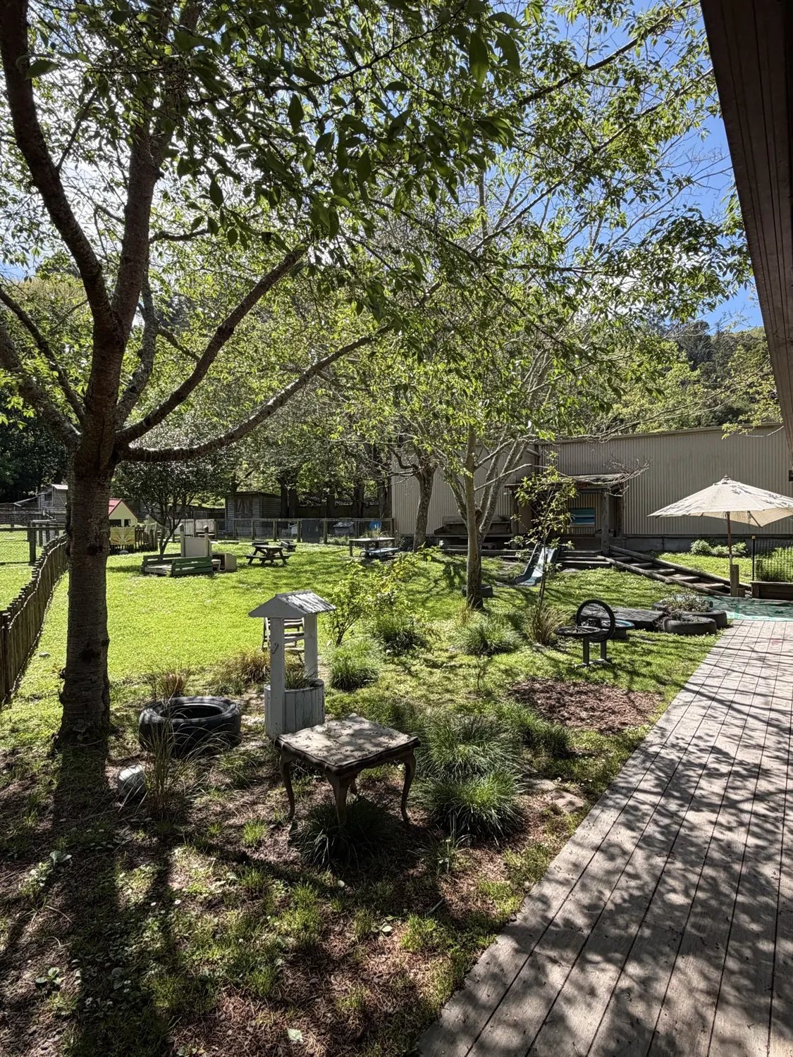 The sunny Panihi garden with a little wishing well, an umbrella and a boardwalk