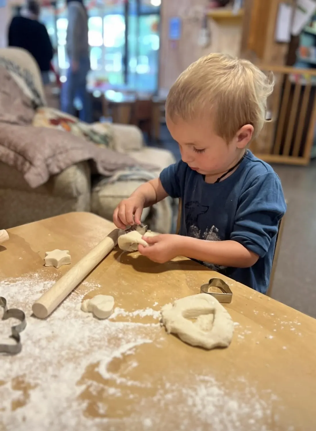 A toddler shaping dough on a floured table