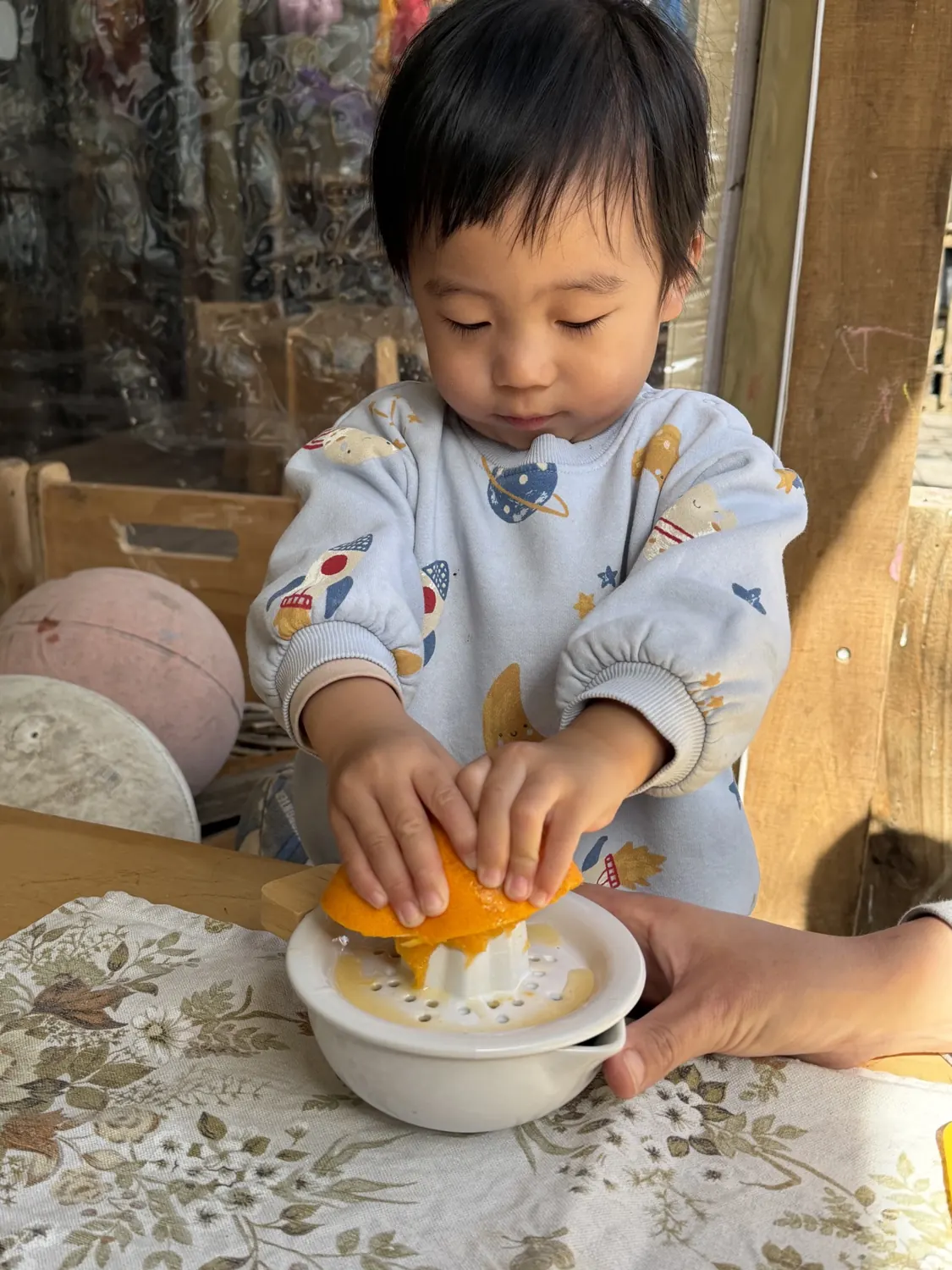 A toddler juicing an orange by themselves