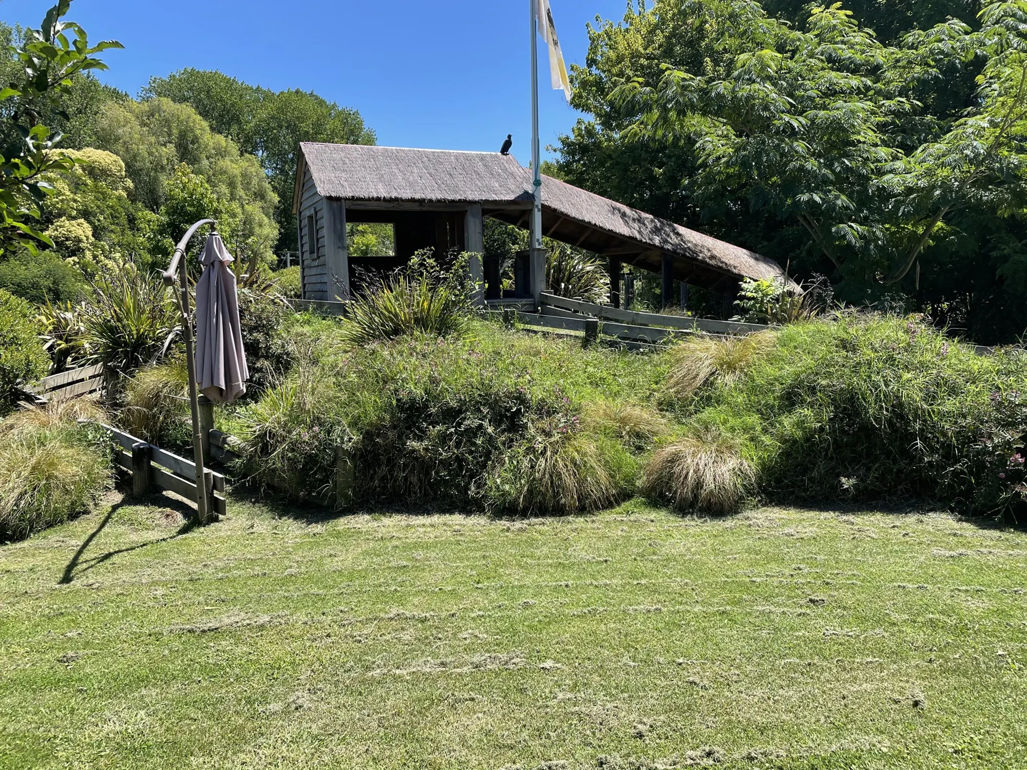 The thatched hut, gardens and lawn at The Farmyard on a sunny day