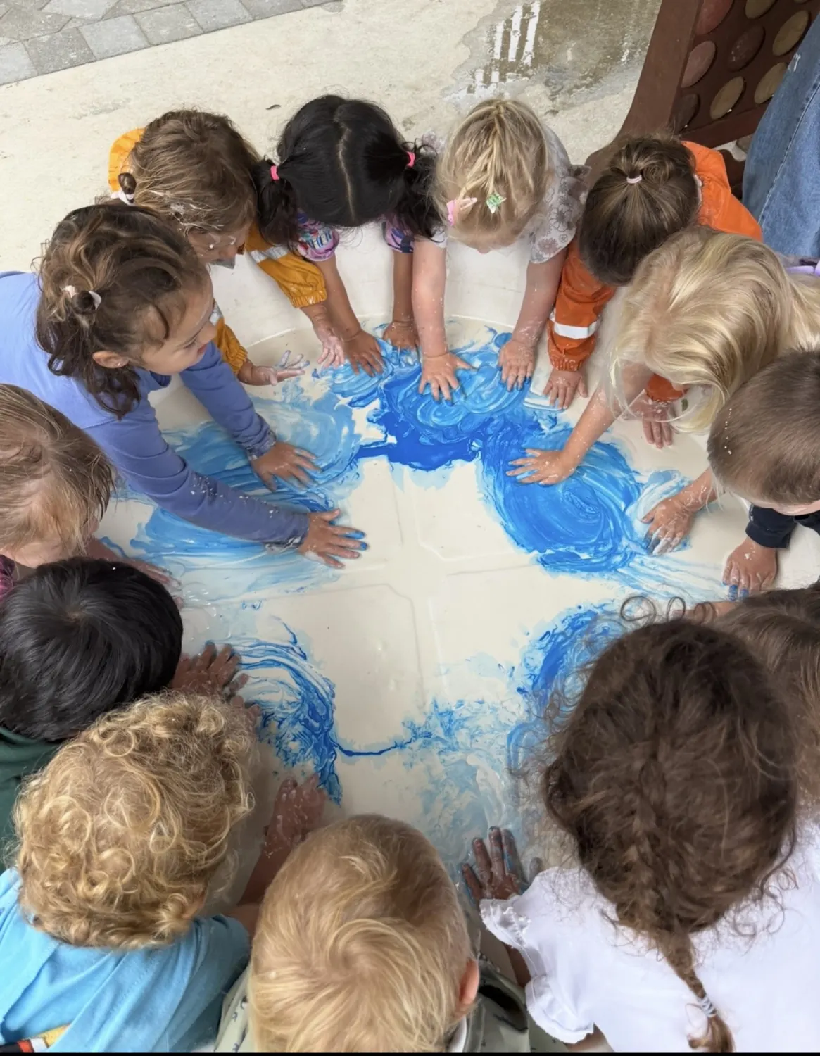 A group of children finger painting together around one table